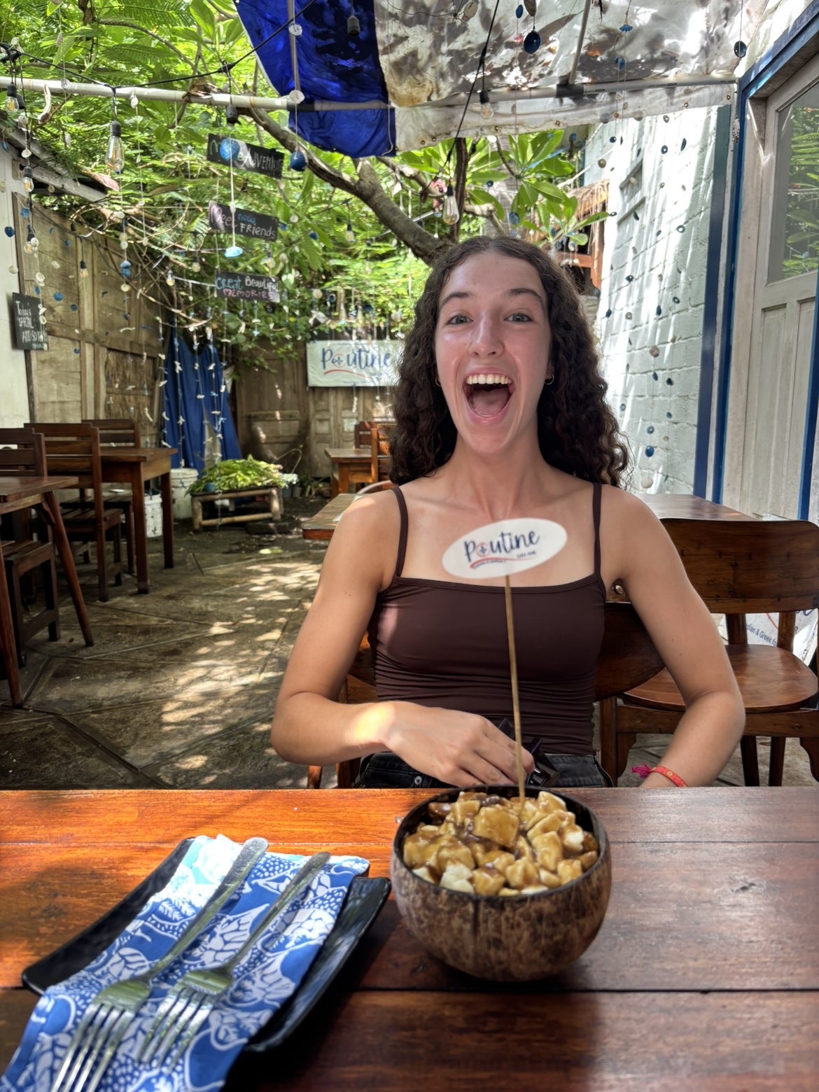 Quebec guest smiling with a Poutine Gili Air sign